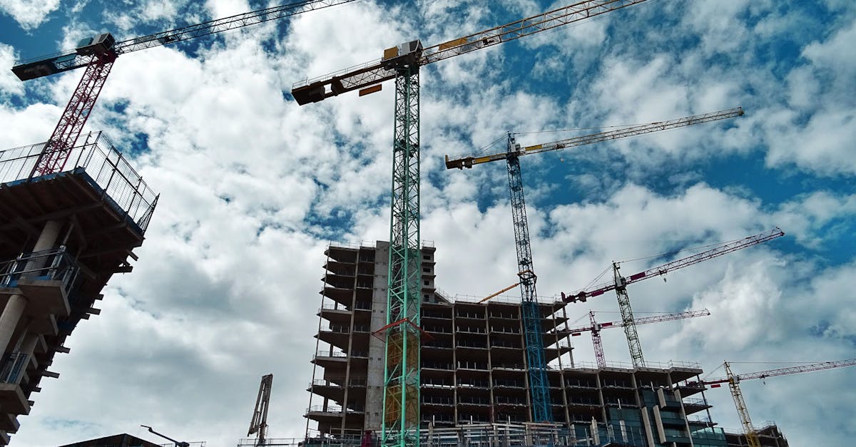 Urban construction site with numerous cranes framing rising skyscrapers against a blue sky.