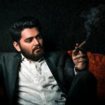 Home Confident man in a suit smoking a cigar, exuding sophistication and style.